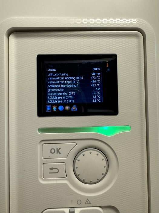 Kontrollpanel för värmesystem med temperaturinformation och status, grå knappar och grön indikatorlampa.