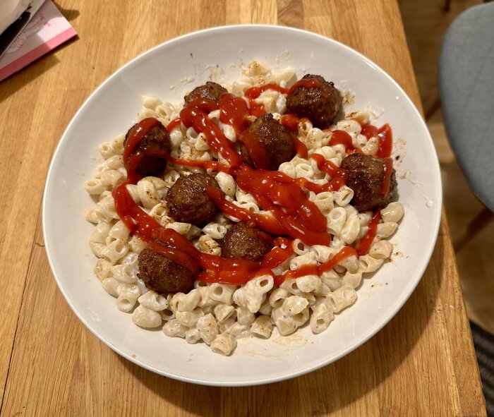 Ett fat med pasta och köttbullar toppat med ketchup.