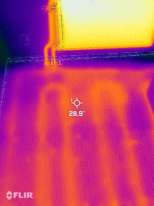 Termisk bild som visar värmeutstrålning, skugga av människor, rum, väggar och fönster. 28,9 °C angivet.