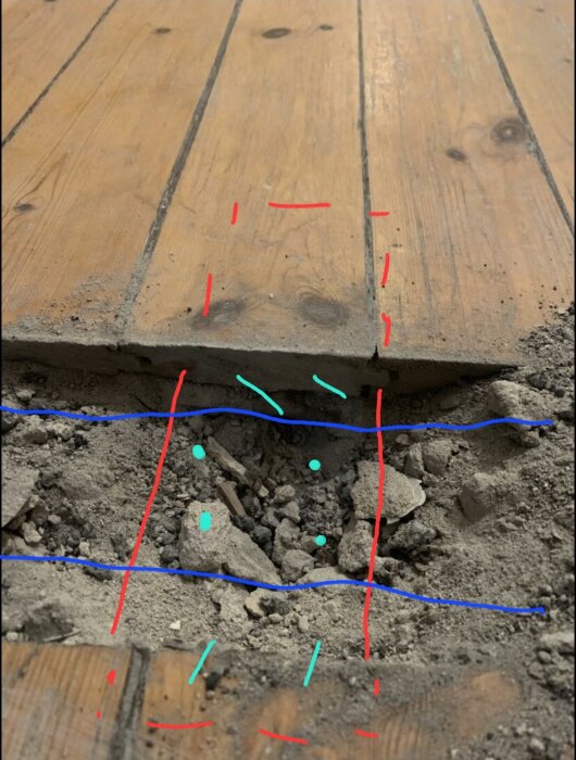 Trägolv och underliggande struktur med synlig skada, röda och blå markeringar illustrerar troligen skadan.
