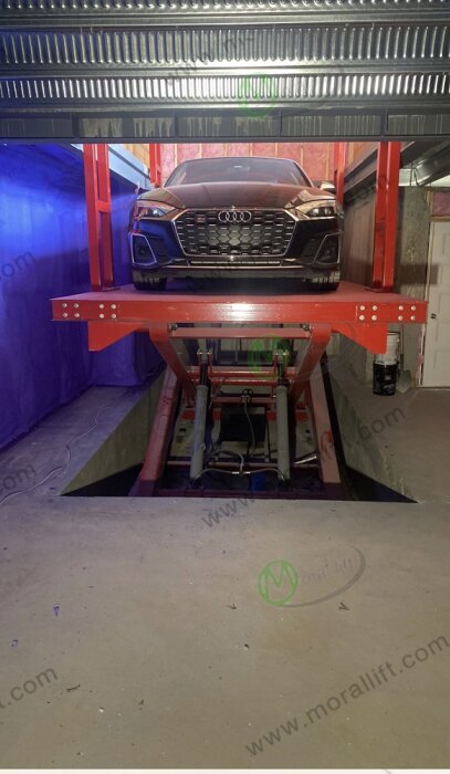 En Audi parkerad på en röd bilhiss i en verkstadsliknande miljö, redo för underhåll eller reparation.