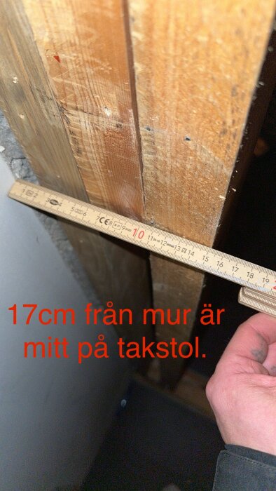 Mätning av avstånd med måttband, 17 cm från mur till träbjälke, möjlig byggnadskontext.