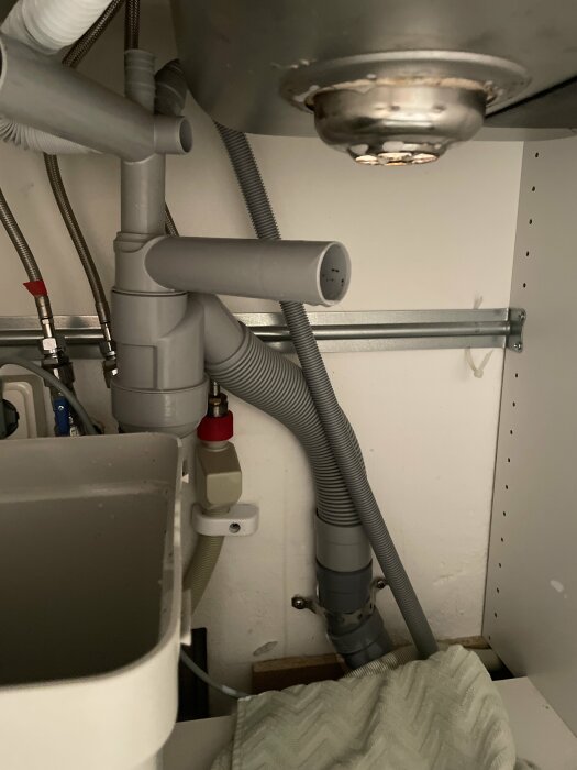 Rörinstallation under diskho, avlopp, flexibla slangar, grått, vitt, ingenjörskonst, hemmamiljö, metallfilter.