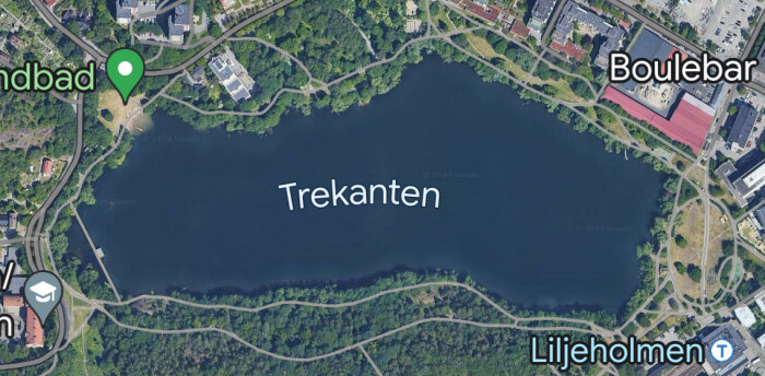Satellitbild av en sjö omgiven av grönområden och bebyggelse, med texten "Trekanter" och intressepunkter markerade.