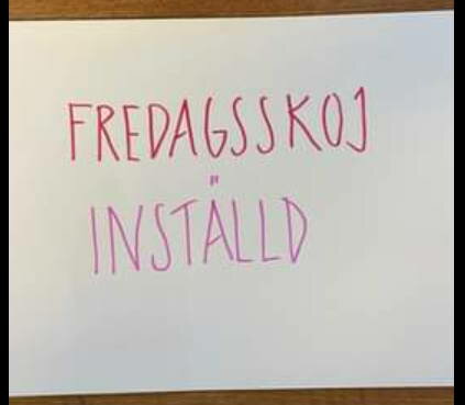 Vitt papper med handskriven text "FREDAGSSKOJ INSTÄLLD" i rosa färg. Enkel bakgrund, nedslående meddelande.