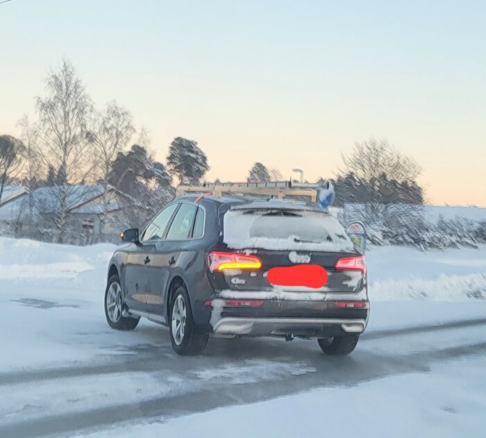 SUV på vinterväg, snöigt landskap, med stege på taket, aningen suddig bild.