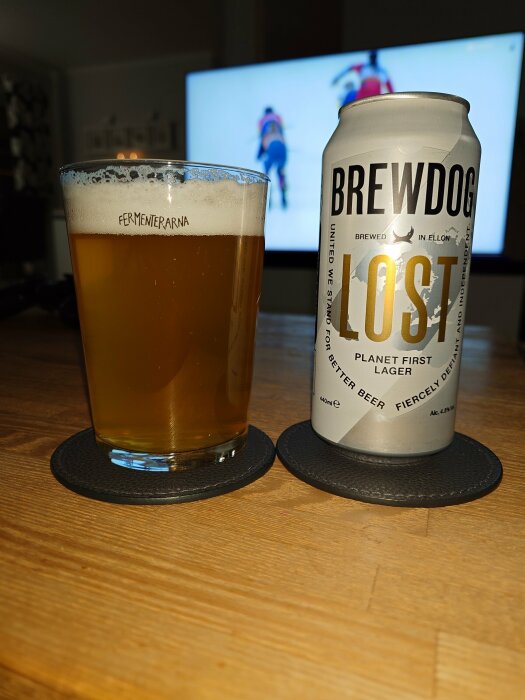 Ölglas på bord, BrewDog burk, skidåkning på TV.