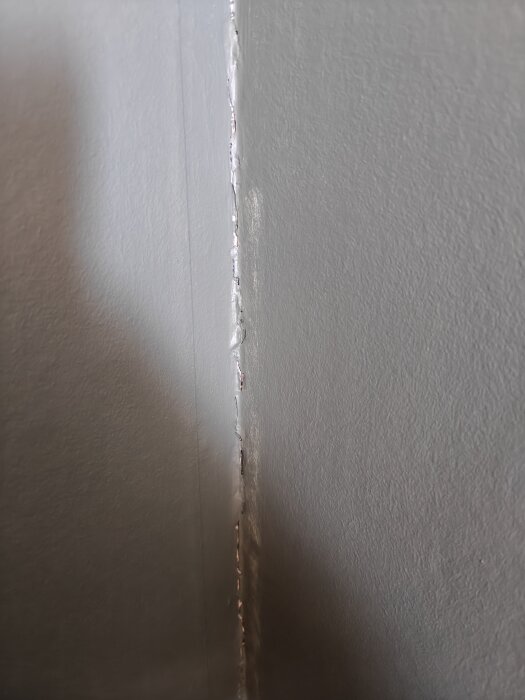En närbild på en spricka i en vägg, krypande från golv till tak, behov av reparation.