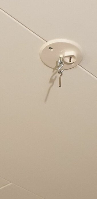 Nycklar i lås på en vit kaklad vägg, med skugga som reflekterar ljuset.