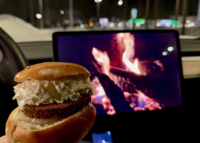 Semla i förgrunden, suddig bakgrund med skärmbild av brasa, bilinredning, mörk utevy.