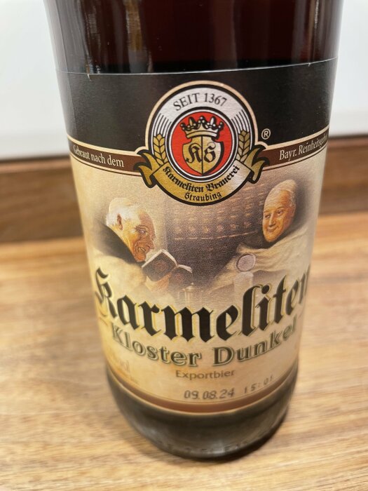 Ölflaska, Karmeliten Kloster Dunkel, Exportbier, sedan 1367, bayersk renhetslag, märkeslogotyp, två personporträtt.