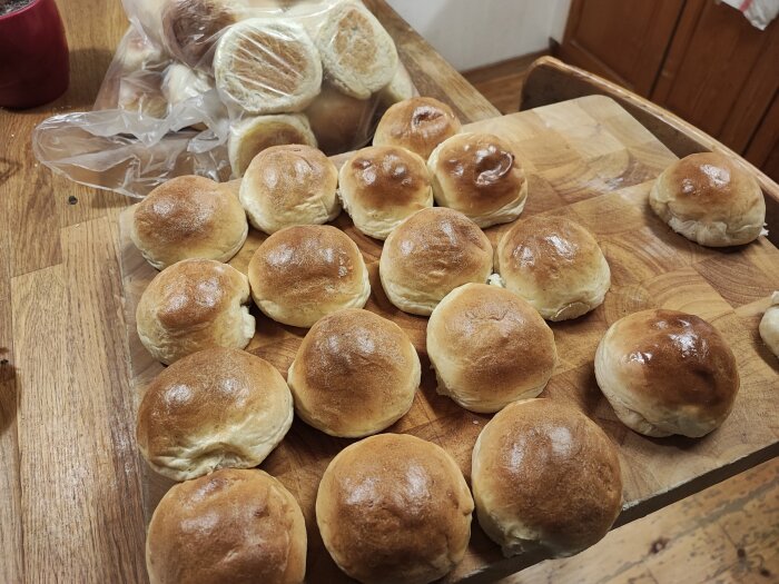 Nybakade bullar på träskärbräda med plastpåse bakom. Hemtrevligt köksmiljö.