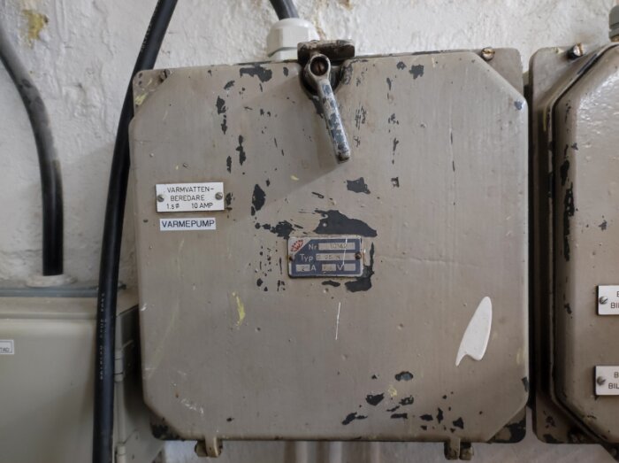 Sliten elektrisk apparatlåda med etiketter, handtag, använd och nött yta, kablar, vit bakgrund.