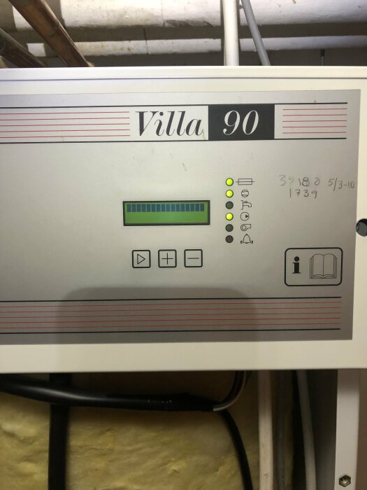 Värmepumpens kontrollpanel märkt "Villa 90", indikatorer, knappar, handskrivna siffror, isolering i bakgrunden.