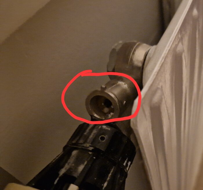 Avskalad dörrhandtagsmekanism, saknar handtaget, roterande del för synlig låsmekanism, nära vägg, röd cirkel markerar fokusområdet.