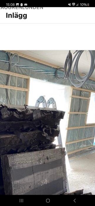 Konstruktion plats, högar av material, flip-flops på en stege, genomskinlig plastskydd, kablar längst taket.