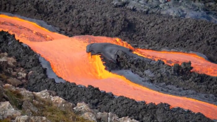 Glödande lava flyter från vulkan, bildande härdade ytor och varma strömmar. Dramatisk naturscen, vulkanisk aktivitet.