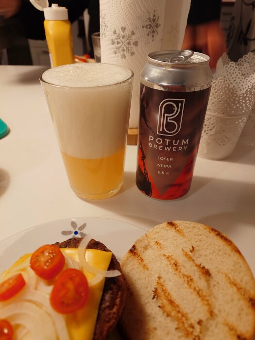 Ölglas med skum, burk från Potum Brewery, hamburgare med lök och tomat.