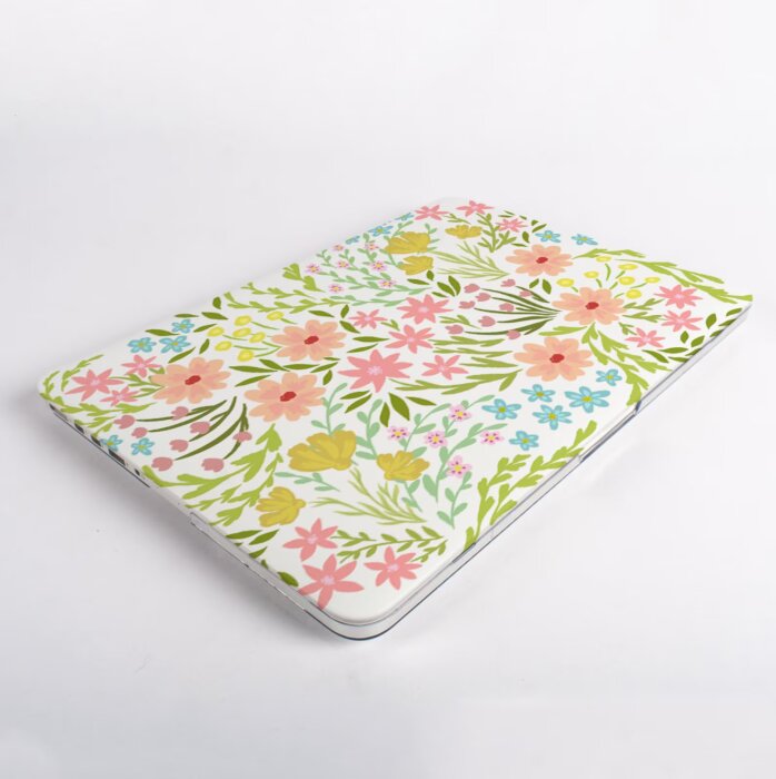 Laptop med blommigt fodral i rosa, gult och grönt mot vit bakgrund.
