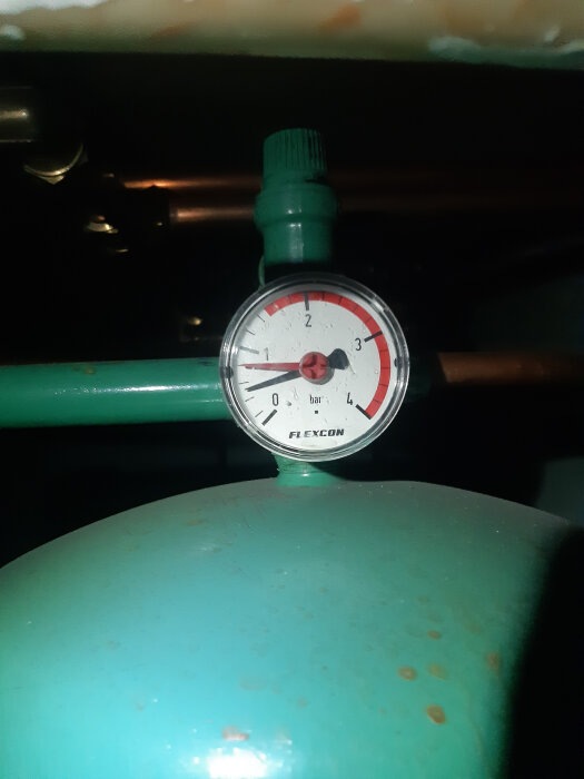 Manometer med grön ratt på en turkos tank; visar ungefär 1,5 bar tryck.