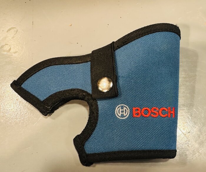 Blå och svart tyghölster för verktyg med BOSCH logo, tryckknapp, ögla för hängande förvaring.