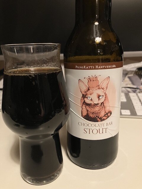 Flaska och glas med mörkt öl, etikett visar katt och text "Chocolate Bar Stout".