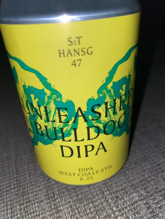 En gul burk med texten "Unleash the Bulldog DIPA" och "WEST COAST-STIL 8,2%" samt blå stänk.