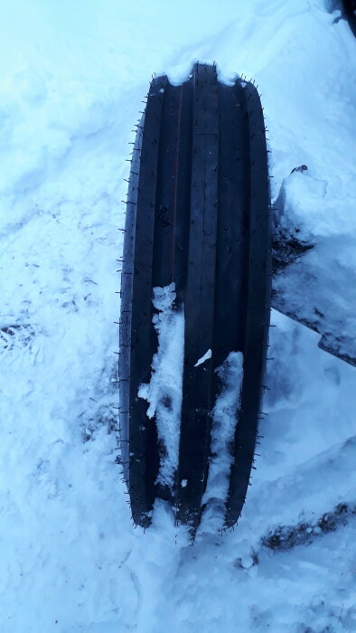 Ett bildäck med dubbar stående i snö.