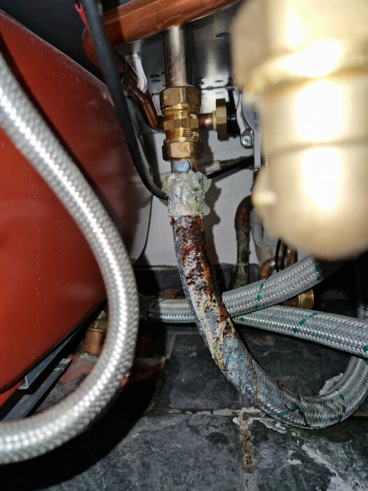 Rostig vattenanslutning med läckage, kalkavlagringar, behöver underhåll eller reparation, i ett mekaniskt rum.