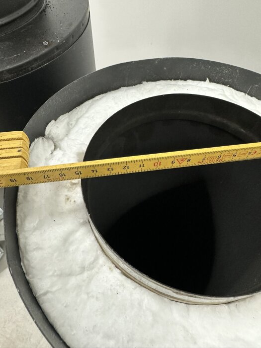 Mätband mäter diameter på isolerat rör, industriellt, med skumisolering, i byggmiljö.