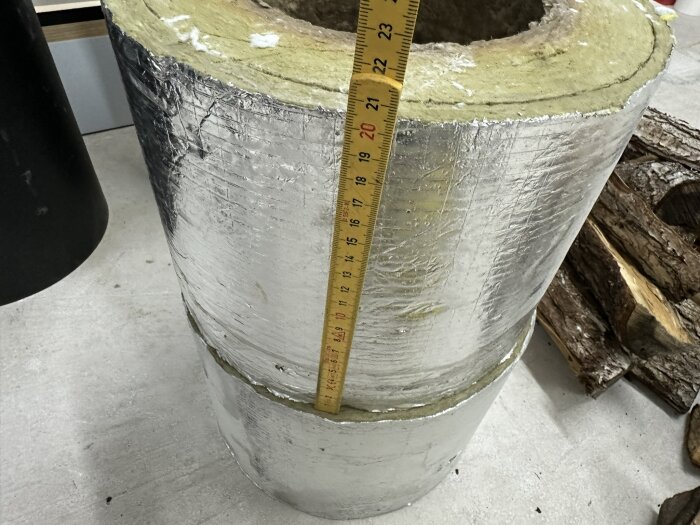 Mätning av stort isolerat rör med tumstock, tjocklek cirka 22 tum.