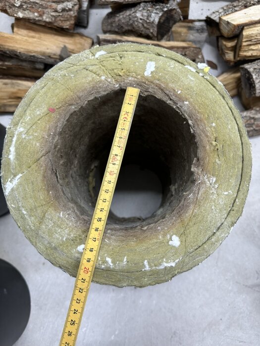 Måttband inuti stor stenhålighet, ved bakom, mäter diametern.