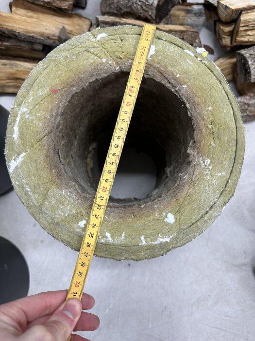 Mätmått mäter hålets diameter på ett grönt, cirkulärt objekt mot vedbakgrund.