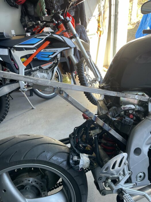 Garage med motorcyklar, en sportcykel demonterad, KTM Freeride, verktyg, utrustning i bakgrunden.