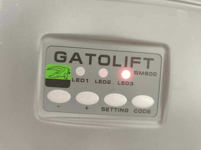 Panel med LED-indikator, knappar, text "GATOLIFT SM600," grön symbol, inställningskod.