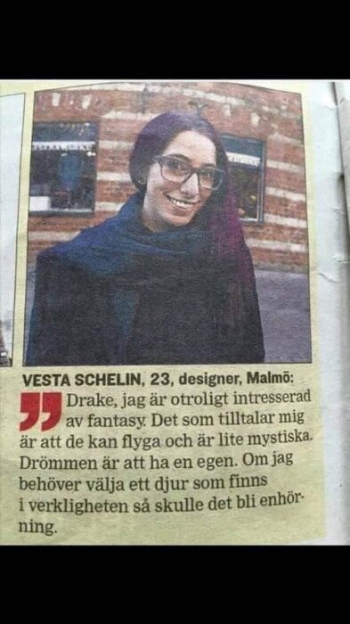 Kvinna i glasögon leende, tidningsutklipp, text om drakar och enhörningar, personlig åsikt.