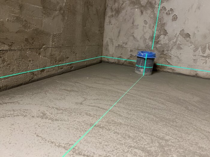 Ett hörn av ett rum under konstruktion med laserlinjer och en burk.