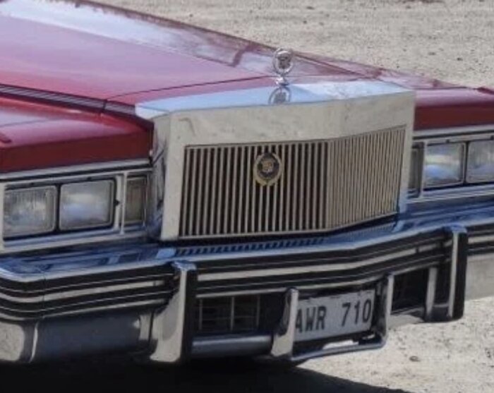 Klassisk bilfront, emblem, grill, strålkastare, nummerskylt, kromdetaljer, röd lack, årgångsstil.