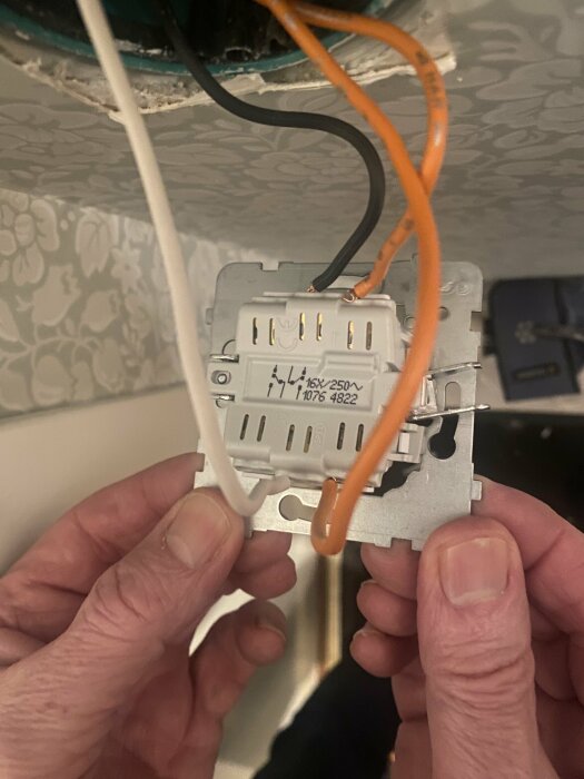 Installation eller reparation av en elektrisk vägguttag, synliga elektriska kablar, händer som arbetar.