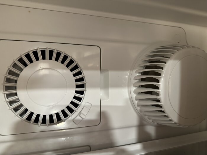 Vit plast, ventilationsgaller och fläktdel, del av hushållsapparat, kylskåp eller luftkonditionering, närbild.