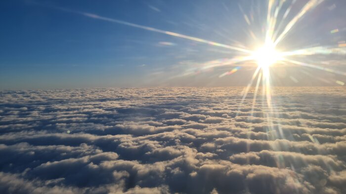 Soluppgång eller solnedgång ovanför tjocka molntäcke, himmel, solstrålar, flygutsikt, klar och fredlig atmosfär.