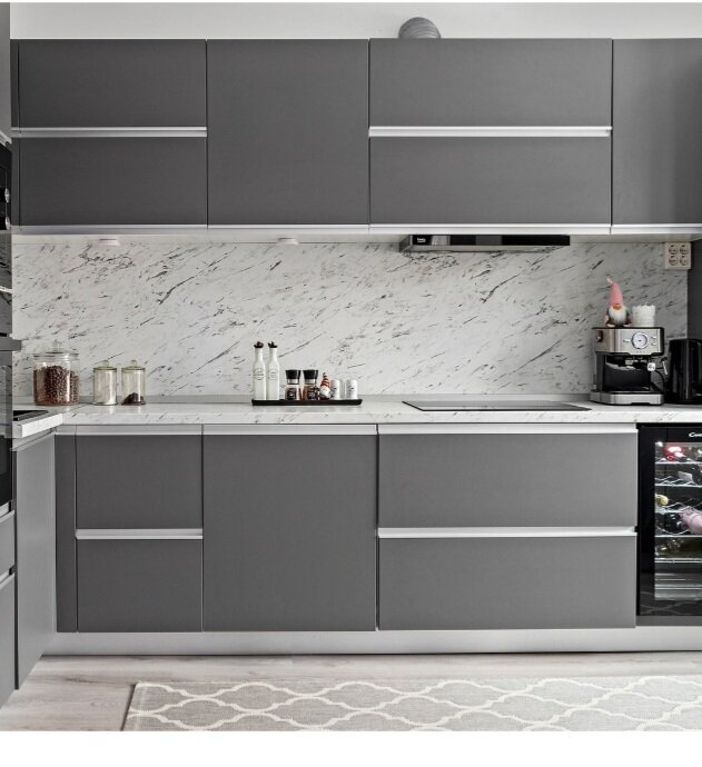 Modernt kök med mörkgrå skåp, marmormönstrad stänkskydd, bänkskiva och kaffemaskin.