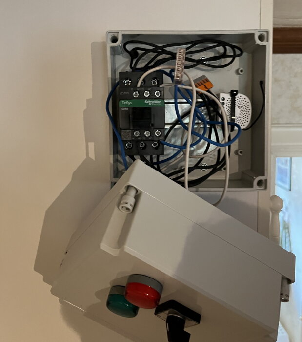 Öppet elskåp med kablar, säkerhetsbrytare och relä. Oorganiserat, installationsarbete pågår eller underhåll.