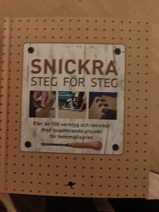 En hantverksbok med titeln "SNICKRA STEG FÖR STEG" med bilder på verktyg och träbearbetning, för hemmafixare.