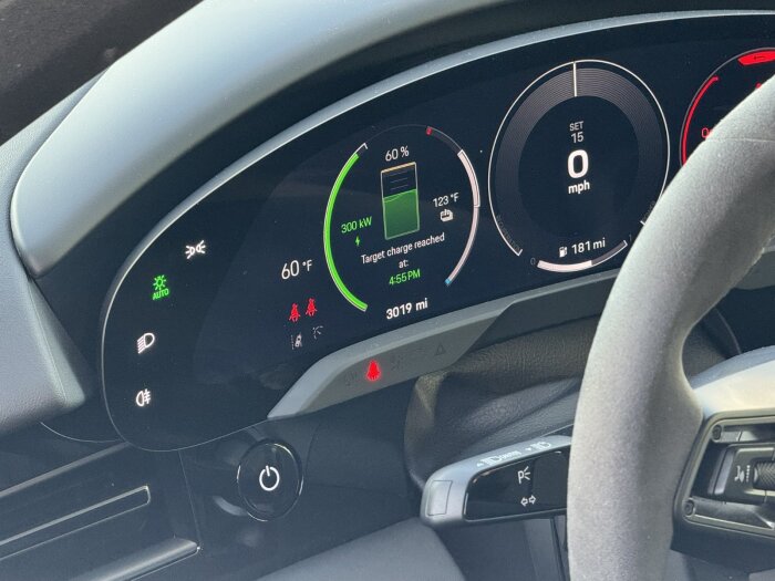 Digital instrumentpanel i bil, visar hastighet, laddning och räckvidd för elbil, plus fordonskontroller.