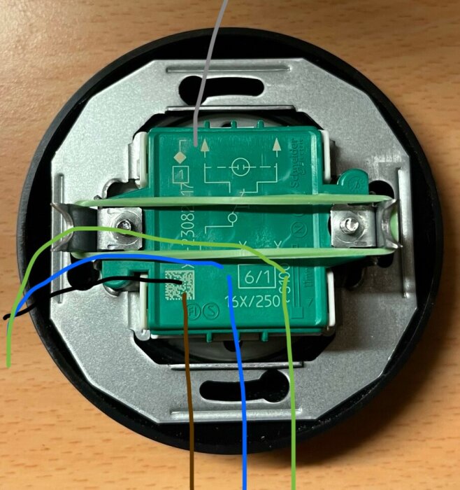 Elektrisk apparat, troligen termostat, öppnad med synliga ledningar, elektronikkomponenter, fastsättningselement.