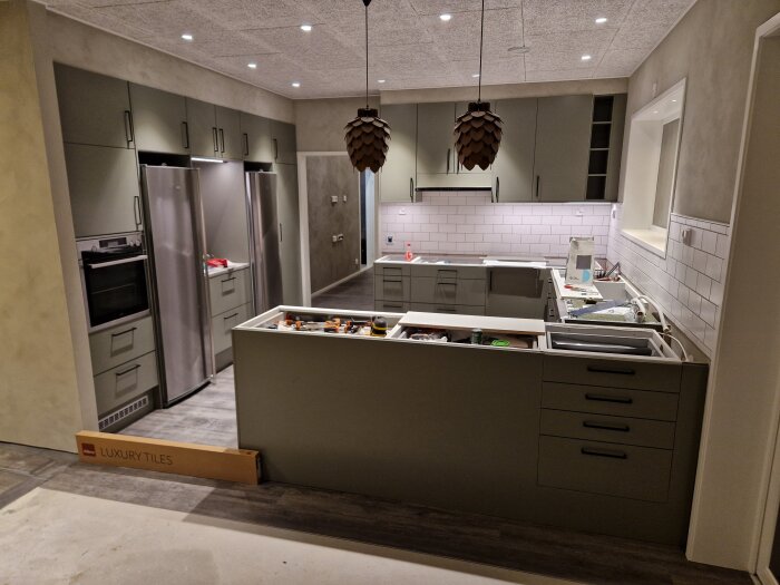 Ett modernt kök under installation eller renovering med öppna lådor och verktyg synliga.