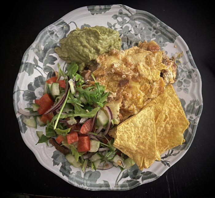 Tallrik med mexikanskinspirerad mat, nachos, guacamole och färsk sallad.