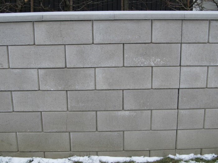Mur av betongblock, snö på marken, ingen synlig himmel eller människor.