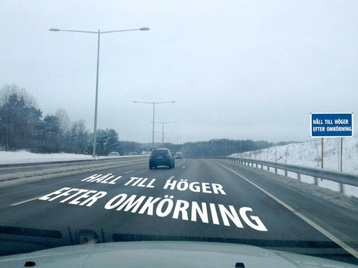 Vinterdag, bil på motorväg, vägmarkering "Håll till höger efter omkörning", skylt, snölandskap.